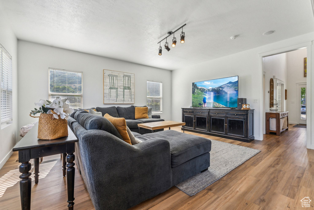 Living room with a textured ceiling, dark wood-type flooring, and rail lighting