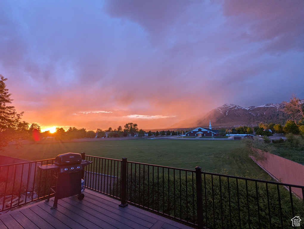 Deck at dusk featuring a mountain view and a lawn