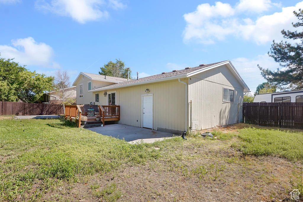 Back of property with a wooden deck and a lawn