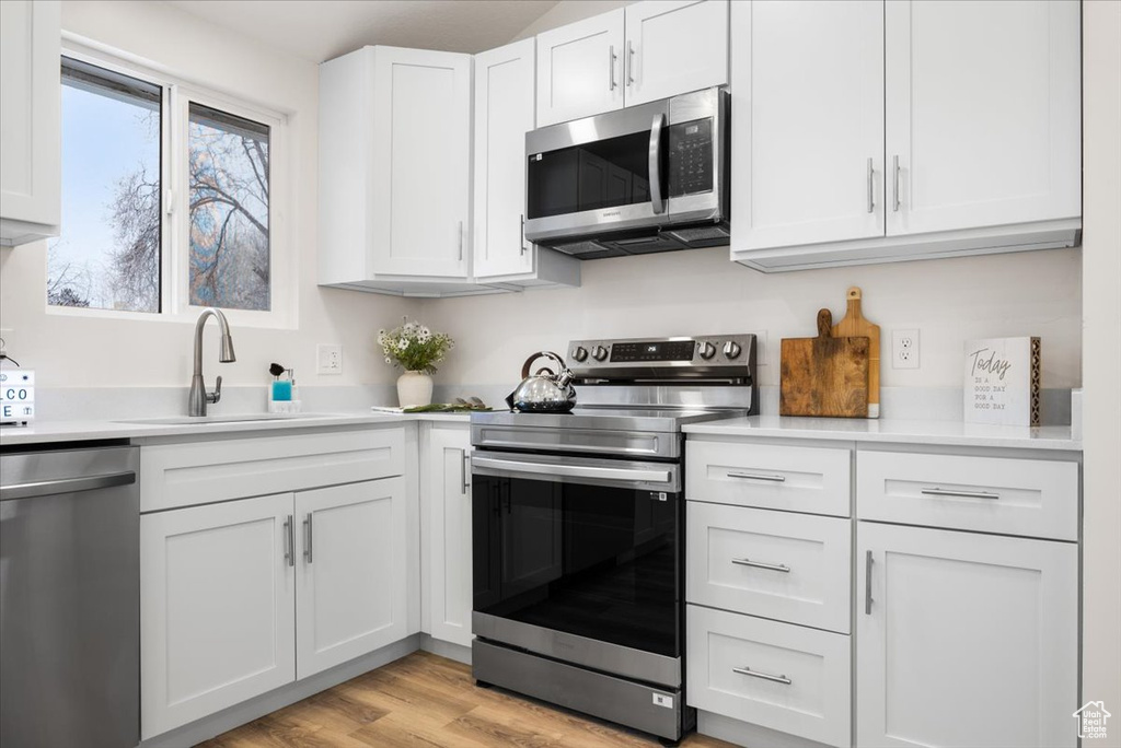 Kitchen featuring white cabinetry, sink, stainless steel appliances, and light hardwood / wood-style flooring