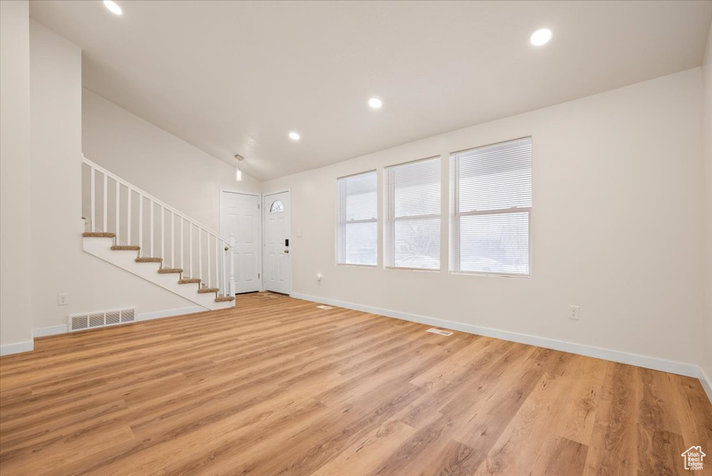 Unfurnished living room with light wood-type flooring and lofted ceiling