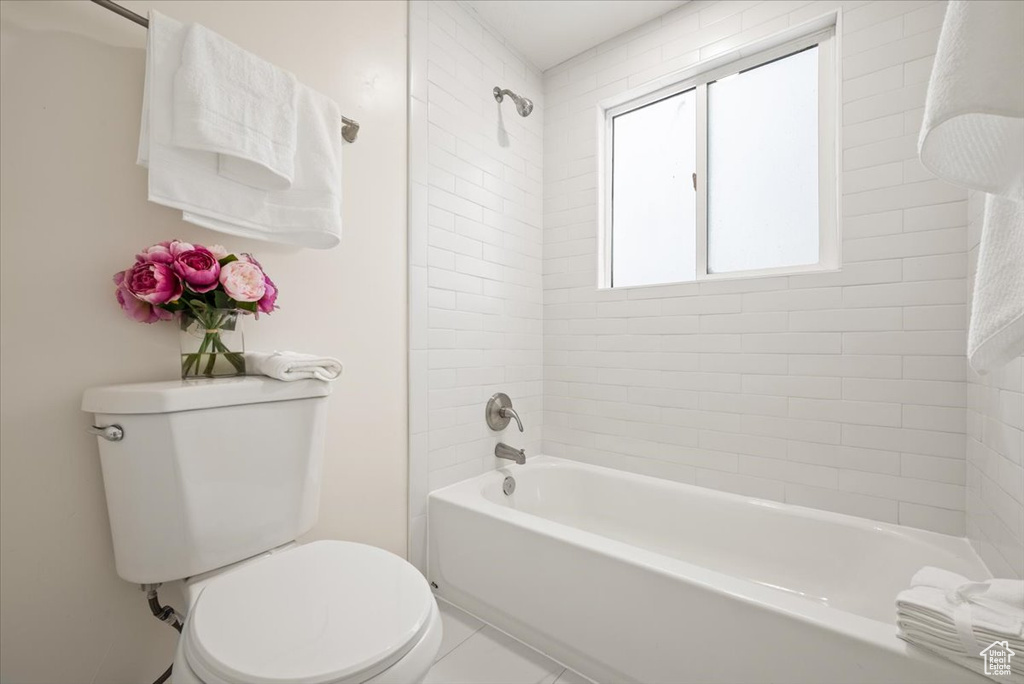 Bathroom featuring toilet, tiled shower / bath combo, and tile patterned floors