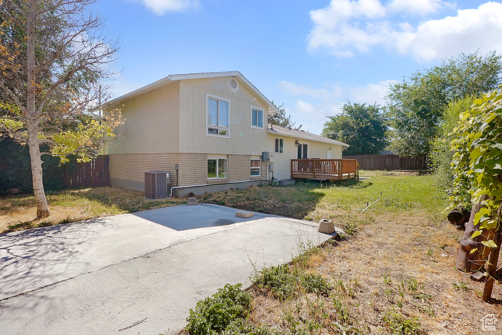 Rear view of property with central AC unit, a deck, and a yard