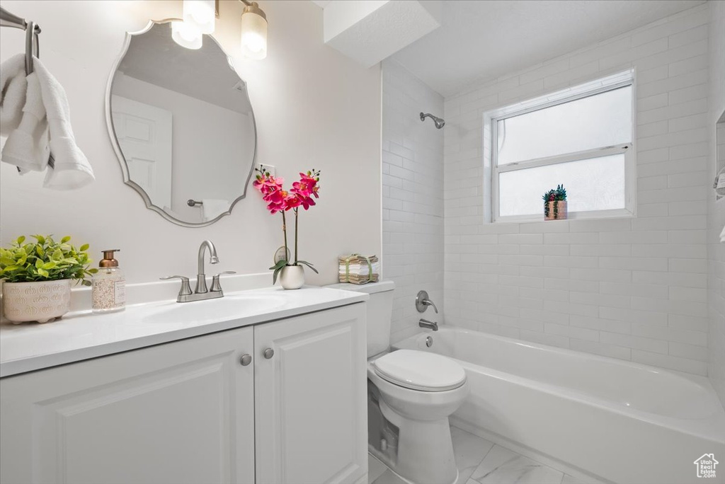 Full bathroom with tile patterned flooring, vanity, tiled shower / bath combo, and toilet