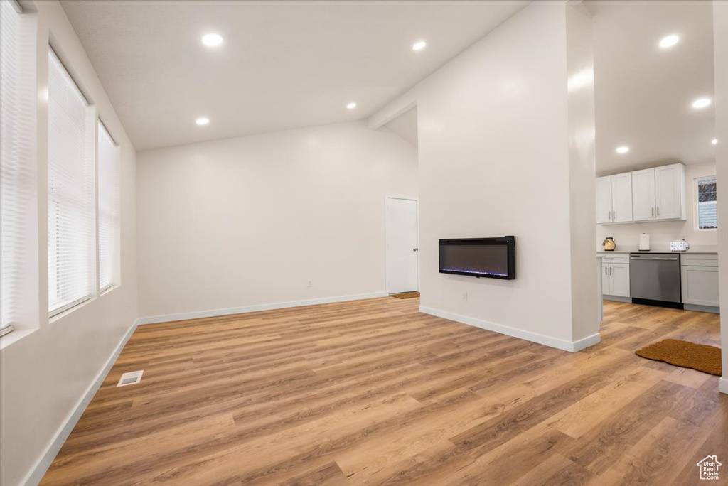 Unfurnished living room with light hardwood / wood-style flooring, high vaulted ceiling, and beam ceiling