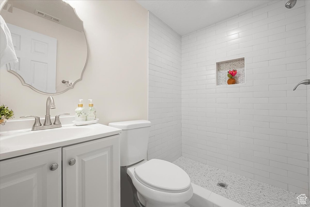 Bathroom with a tile shower, vanity, and toilet