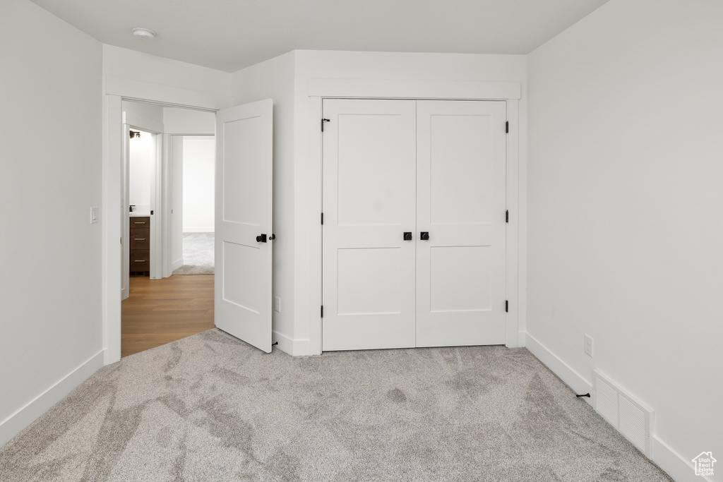 Unfurnished bedroom with a closet and light colored carpet