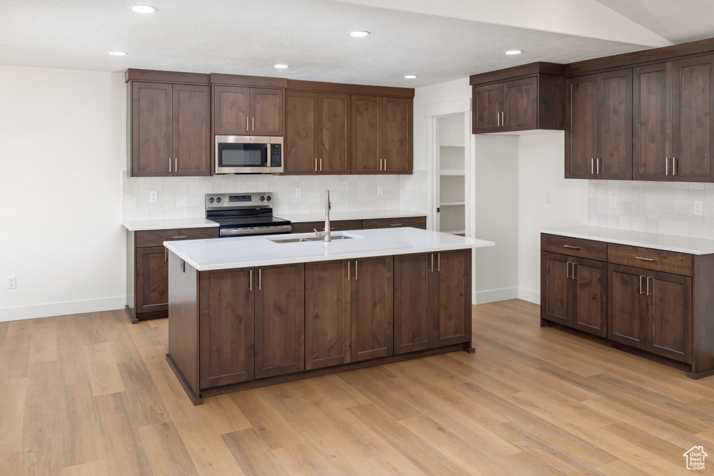 Kitchen featuring backsplash, stainless steel appliances, light hardwood / wood-style floors, dark brown cabinets, and sink