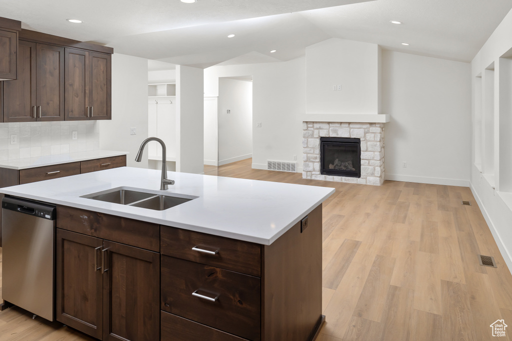 Kitchen featuring sink, a fireplace, light wood-type flooring, and dishwasher