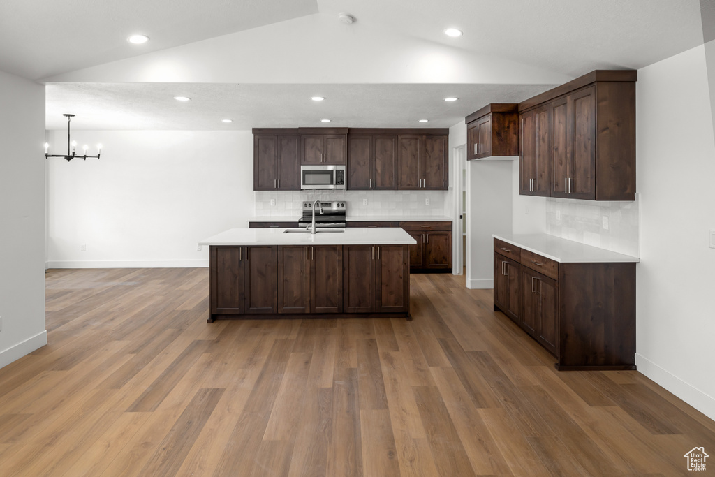 Kitchen with backsplash, wood-type flooring, and dark brown cabinets