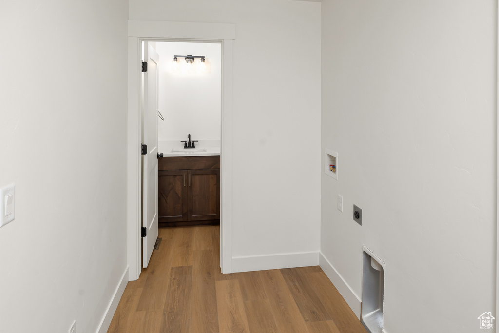 Interior space with sink, washer hookup, electric dryer hookup, and light wood-type flooring