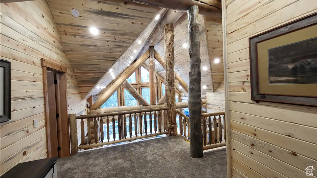 Interior space with vaulted ceiling, carpet floors, wooden ceiling, and wood walls