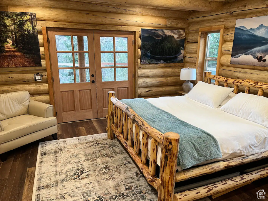 Bedroom with rustic walls and dark hardwood / wood-style flooring