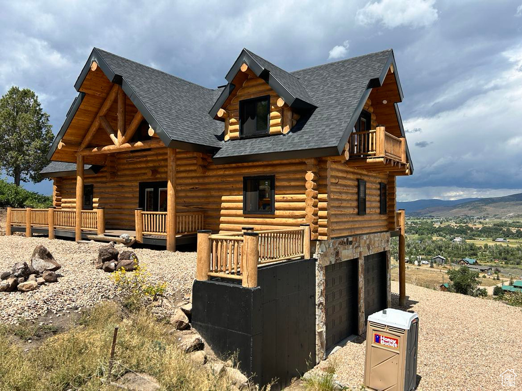 Log-style house featuring a balcony and a garage