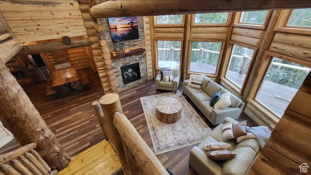 Living room with rustic walls, hardwood / wood-style floors, and a stone fireplace