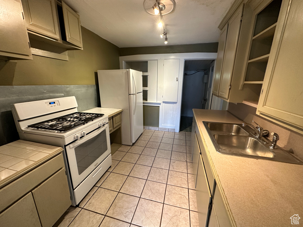 Kitchen with rail lighting, sink, gray cabinetry, light tile patterned floors, and white appliances