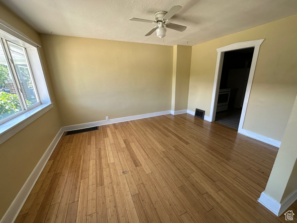 Empty room featuring ceiling fan, hardwood / wood-style flooring, and a textured ceiling