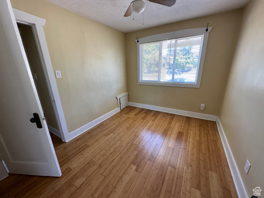 Empty room featuring light wood-type flooring, ceiling fan, and a textured ceiling