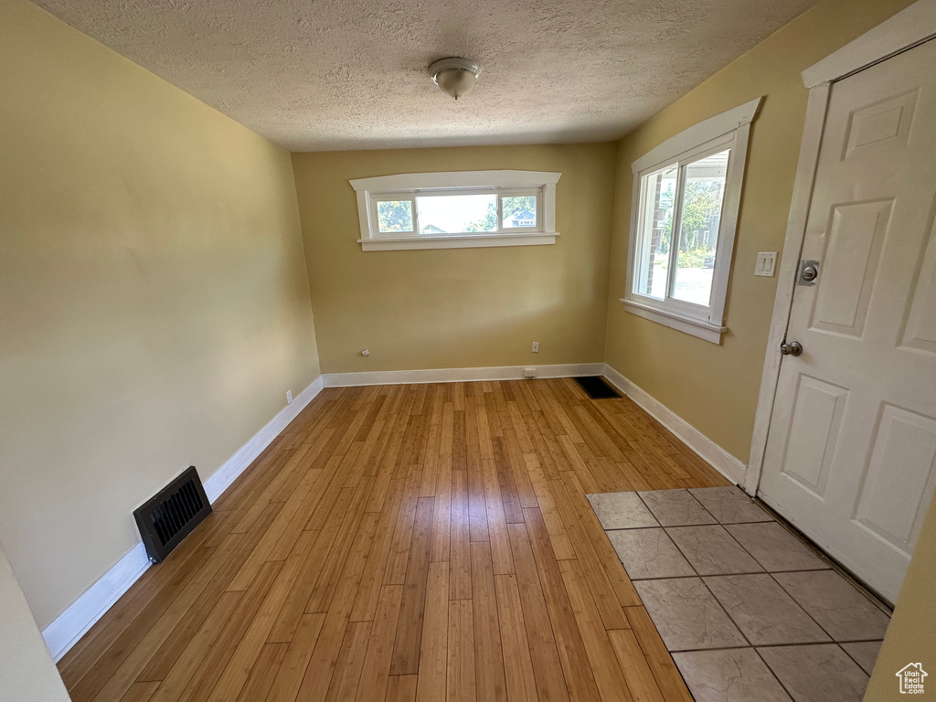 Interior space with a textured ceiling and light hardwood / wood-style floors