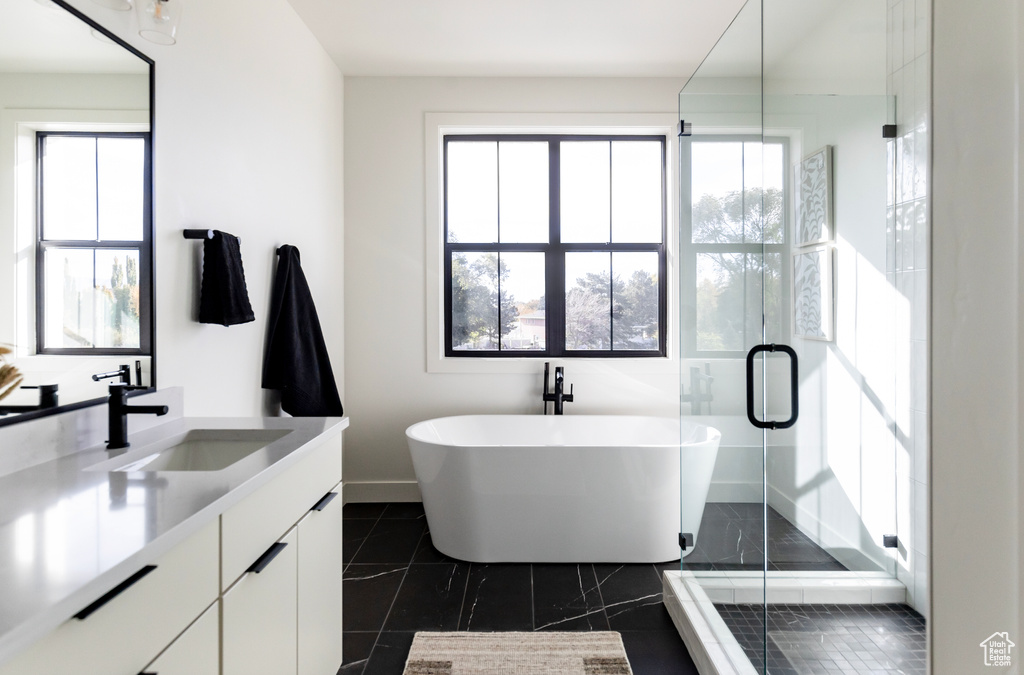 Bathroom featuring tile patterned floors, vanity, and plus walk in shower