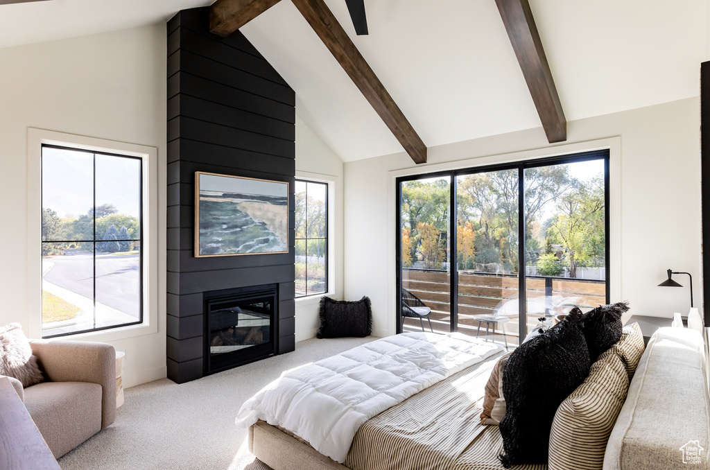 Carpeted bedroom featuring beamed ceiling, a large fireplace, multiple windows, and high vaulted ceiling