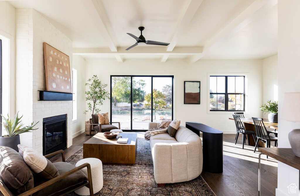 Living room featuring beam ceiling, a fireplace, dark hardwood / wood-style floors, and a healthy amount of sunlight