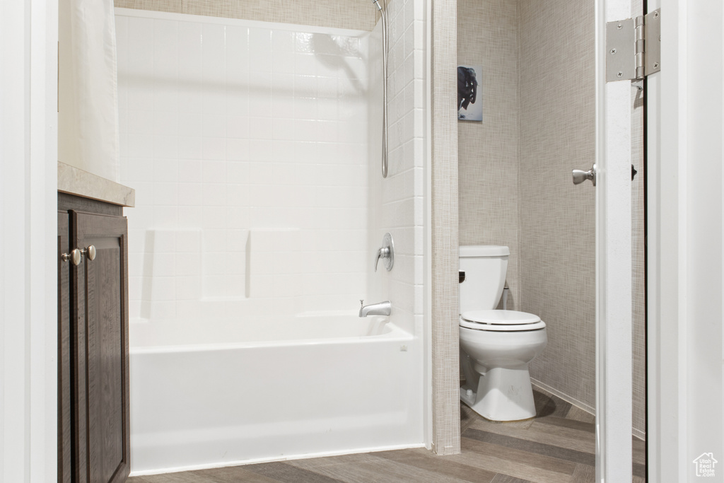 Bathroom featuring hardwood / wood-style floors, shower / bathtub combination, and toilet