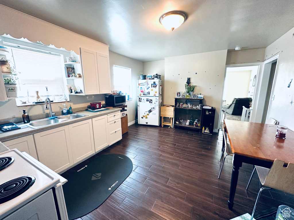 Kitchen with sink, white cabinetry, white fridge, and dark hardwood / wood-style floors