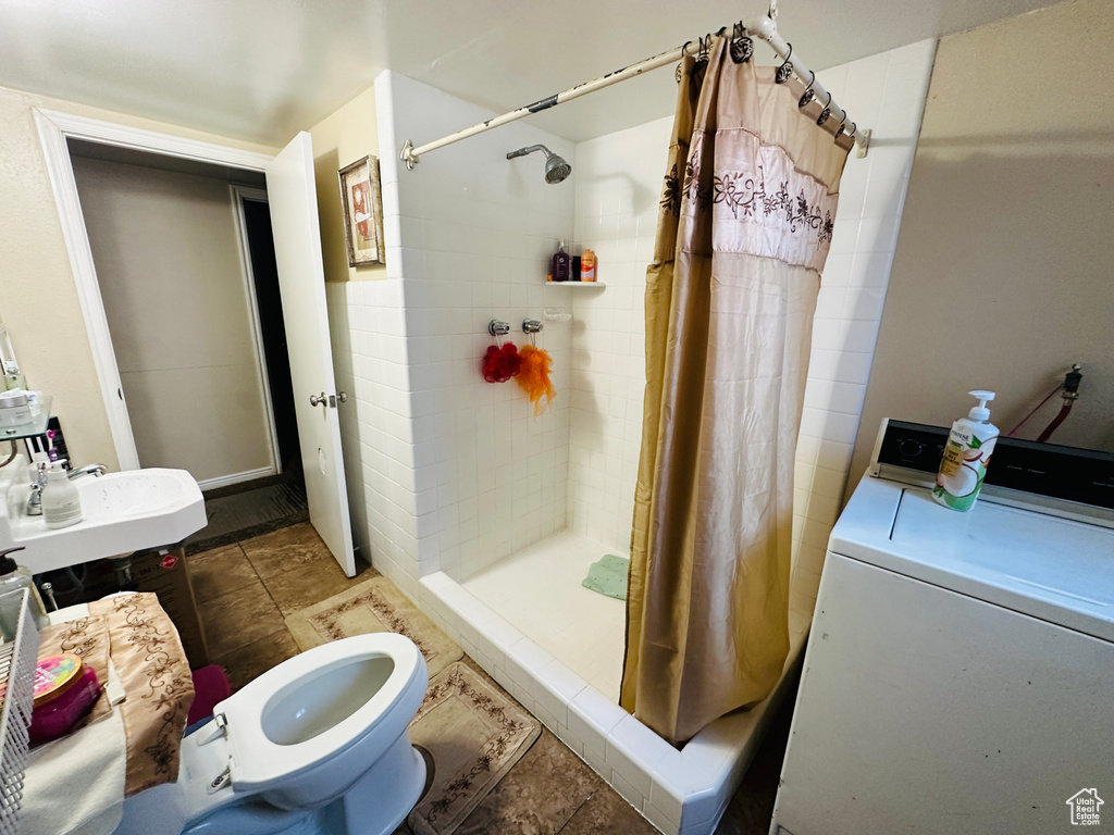 Bathroom featuring tile patterned flooring, washer / clothes dryer, a shower with curtain, and toilet