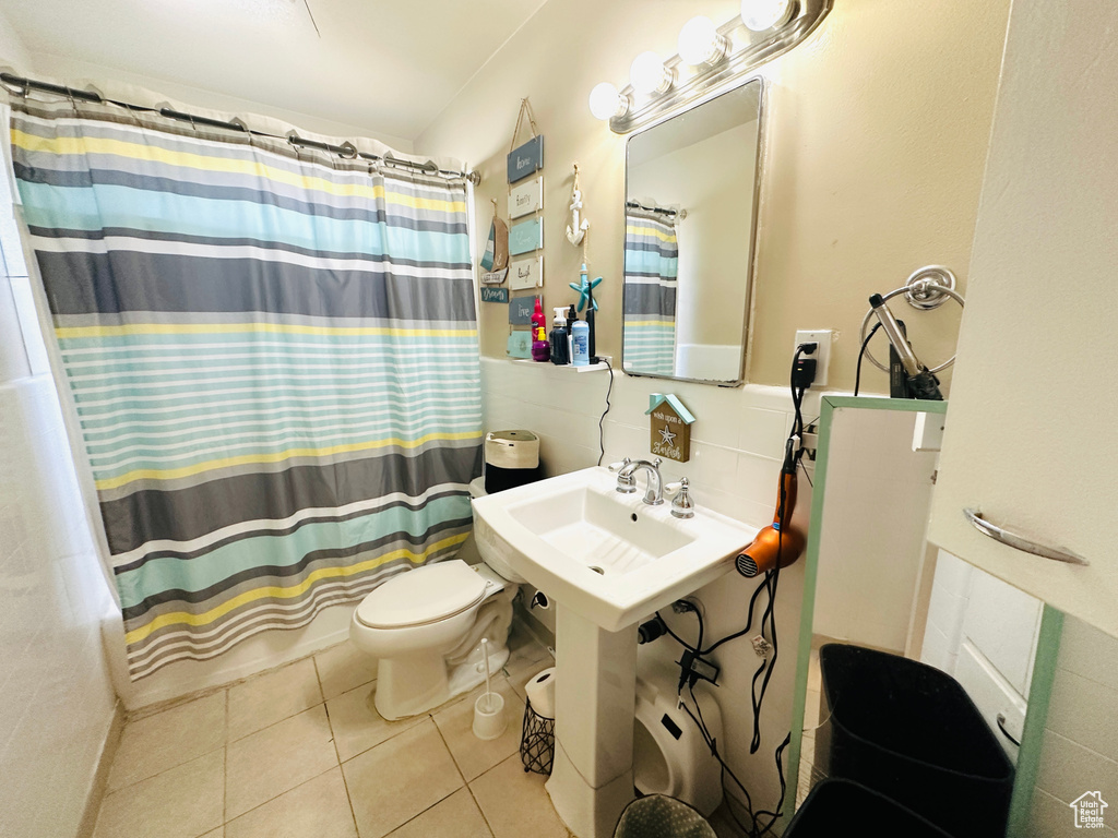 Full bathroom featuring decorative backsplash, shower / bathtub combination with curtain, tile patterned flooring, sink, and toilet