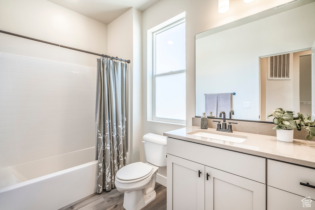 Full bathroom featuring toilet, vanity, hardwood / wood-style flooring, and shower / bathtub combination with curtain