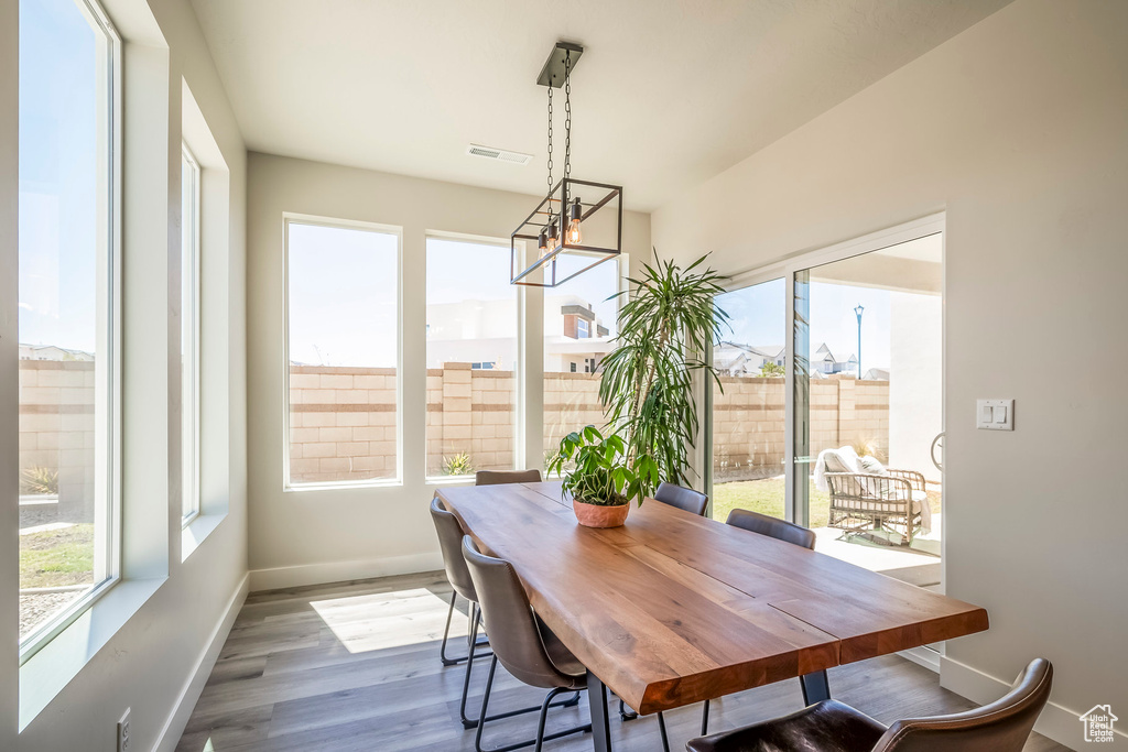 Dining space with a notable chandelier, plenty of natural light, and wood-type flooring