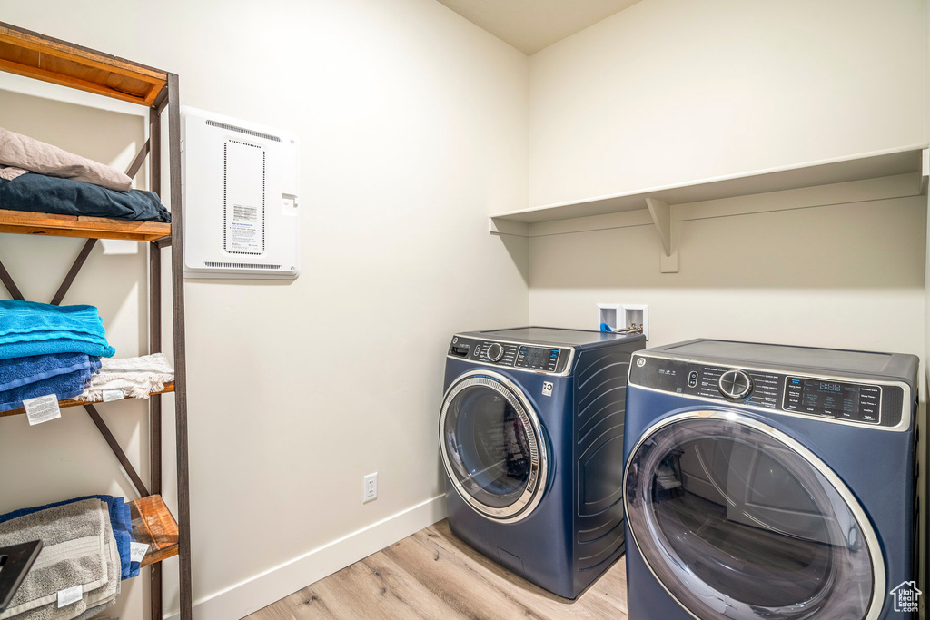 Laundry room with independent washer and dryer and light hardwood / wood-style floors