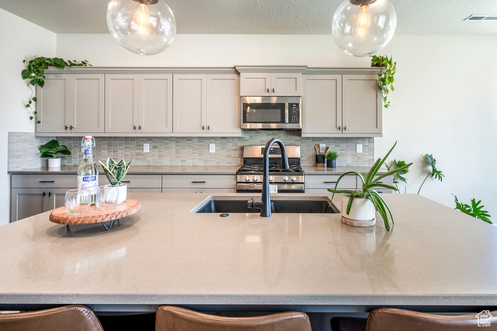 Kitchen with backsplash, appliances with stainless steel finishes, and gray cabinets