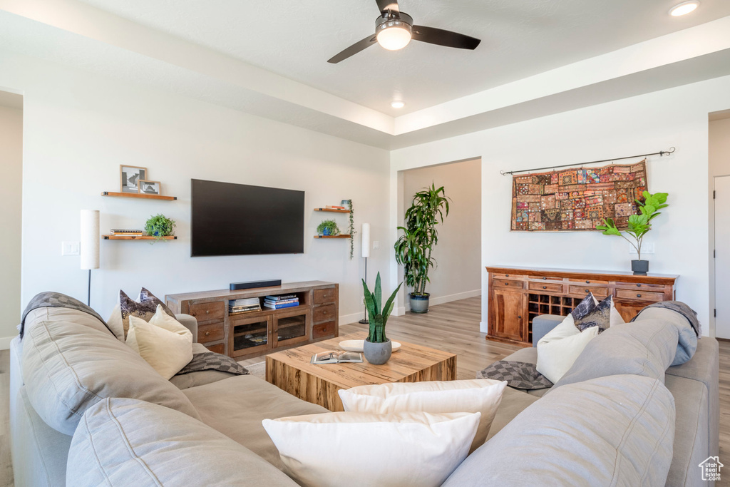 Living room featuring ceiling fan, light hardwood / wood-style flooring, and a tray ceiling