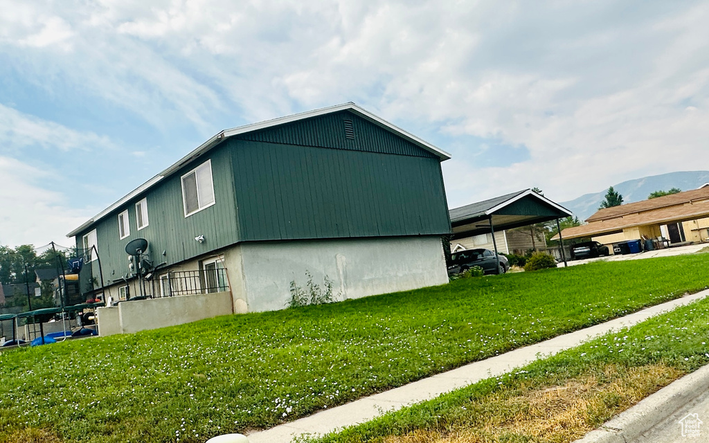 View of home's exterior with a mountain view and a lawn