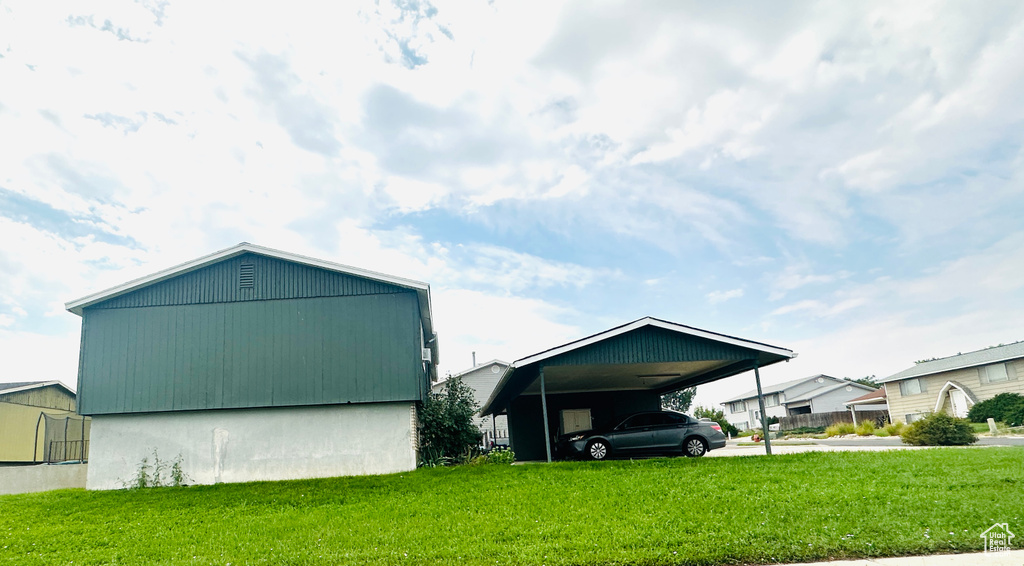 View of outbuilding with a carport and a lawn