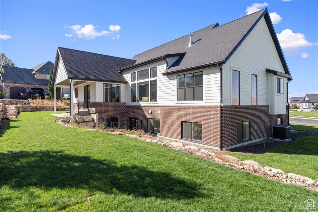 Back of house featuring a yard and central AC