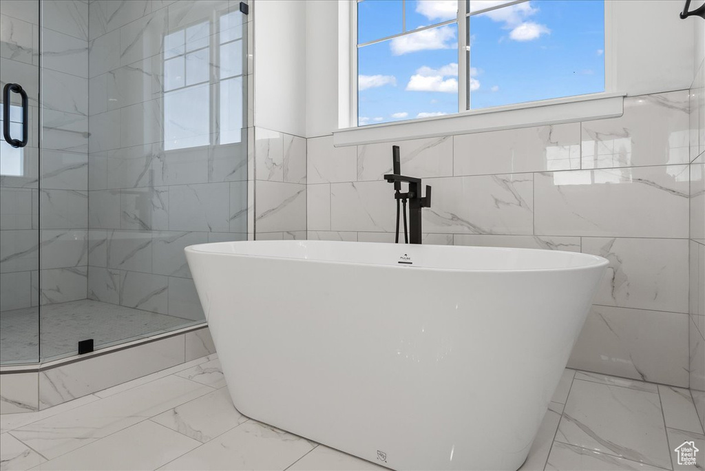 Bathroom featuring tile patterned floors, a shower with door, and tile walls