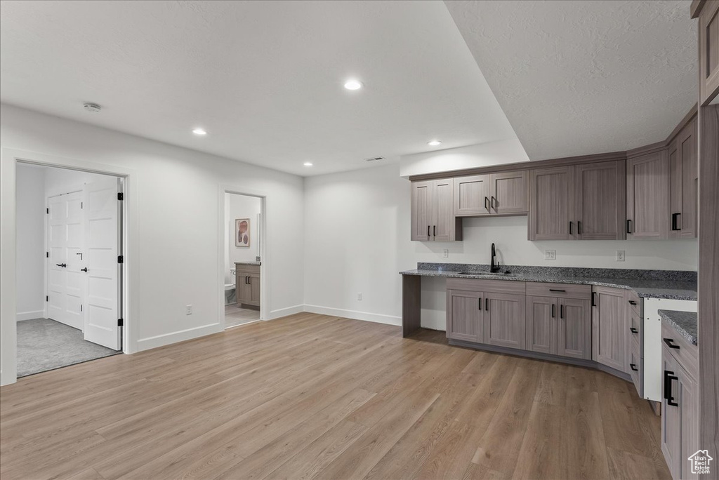 Kitchen with sink, dark stone countertops, and light hardwood / wood-style floors