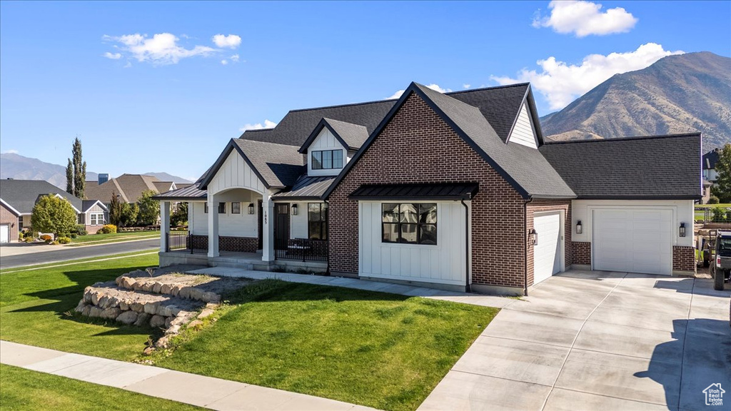 View of front of house with a porch, a garage, a mountain view, and a front yard