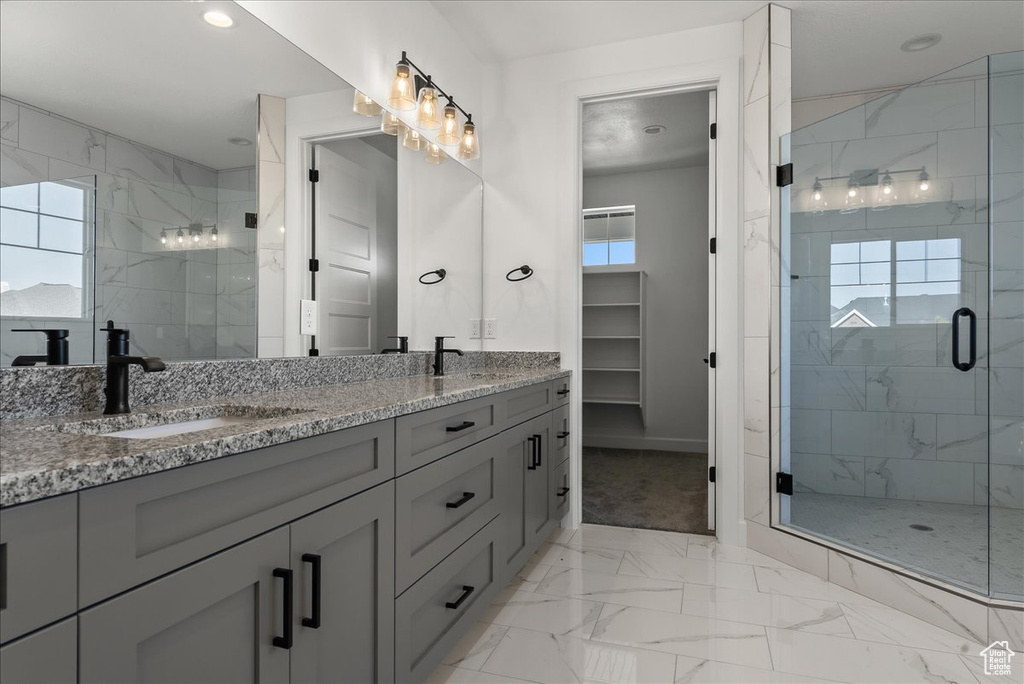 Bathroom featuring dual vanity, tile patterned floors, and an enclosed shower