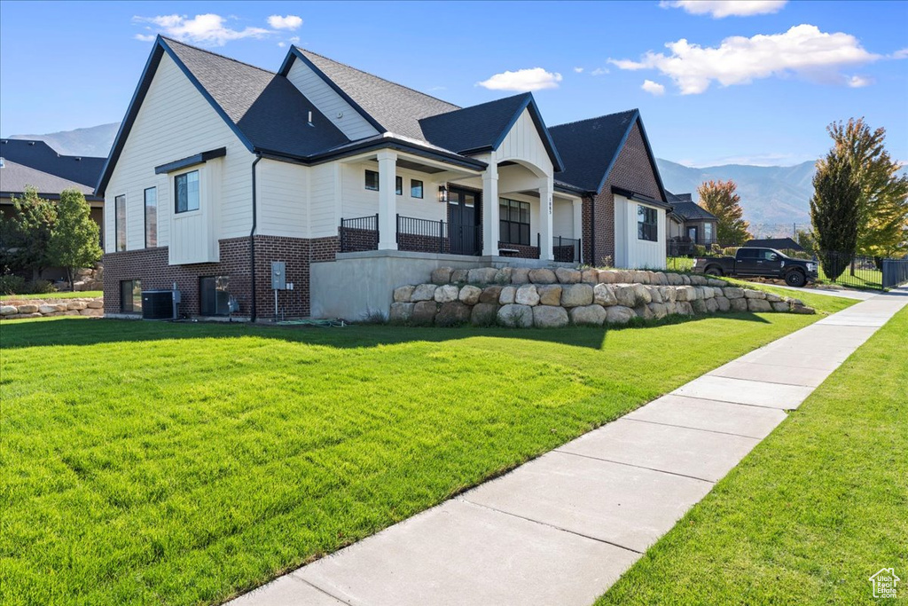 View of side of home featuring a mountain view, a lawn, and central AC