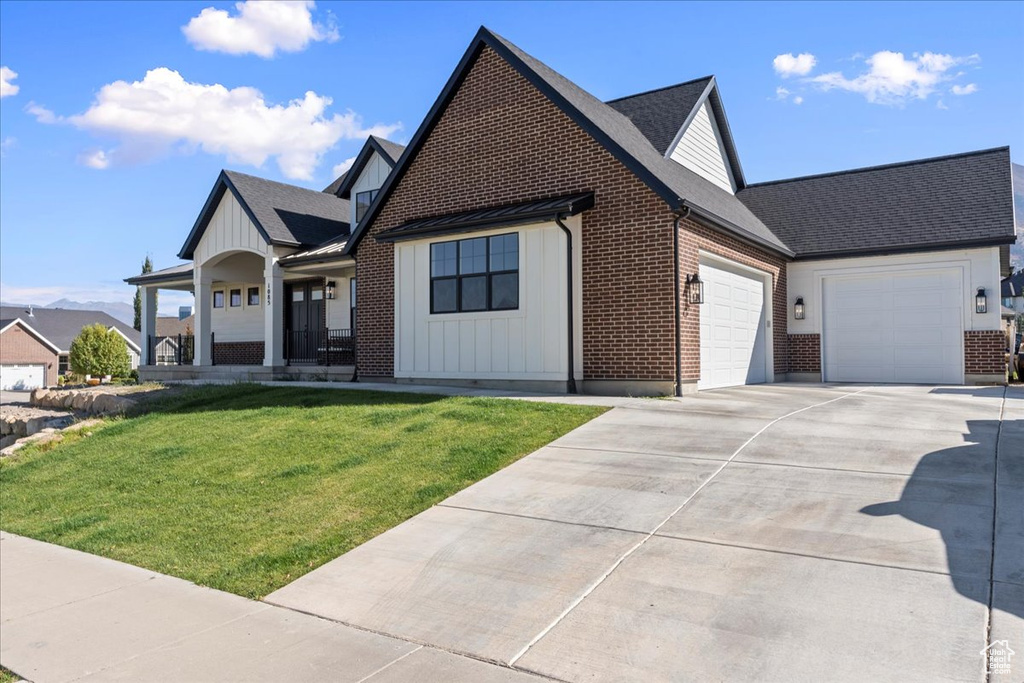 View of front of home featuring a garage, a porch, and a front lawn