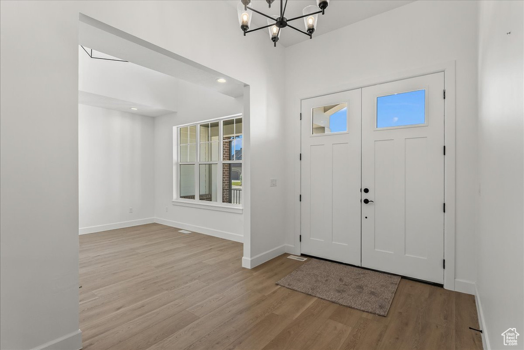 Entrance foyer with an inviting chandelier and light hardwood / wood-style floors