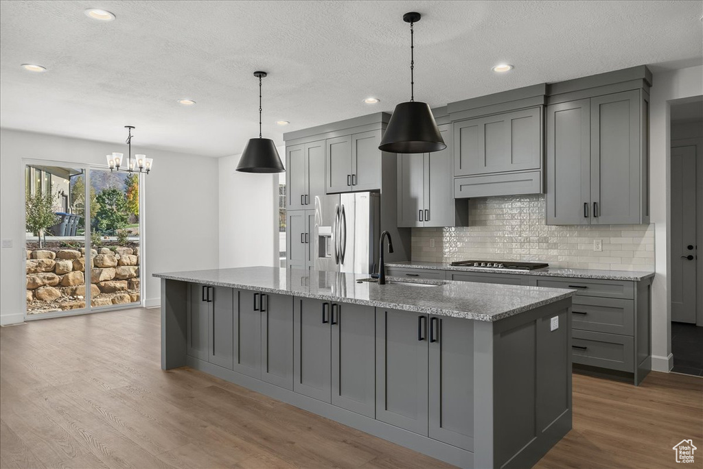 Kitchen with sink, light wood-type flooring, light stone countertops, stainless steel appliances, and gray cabinets