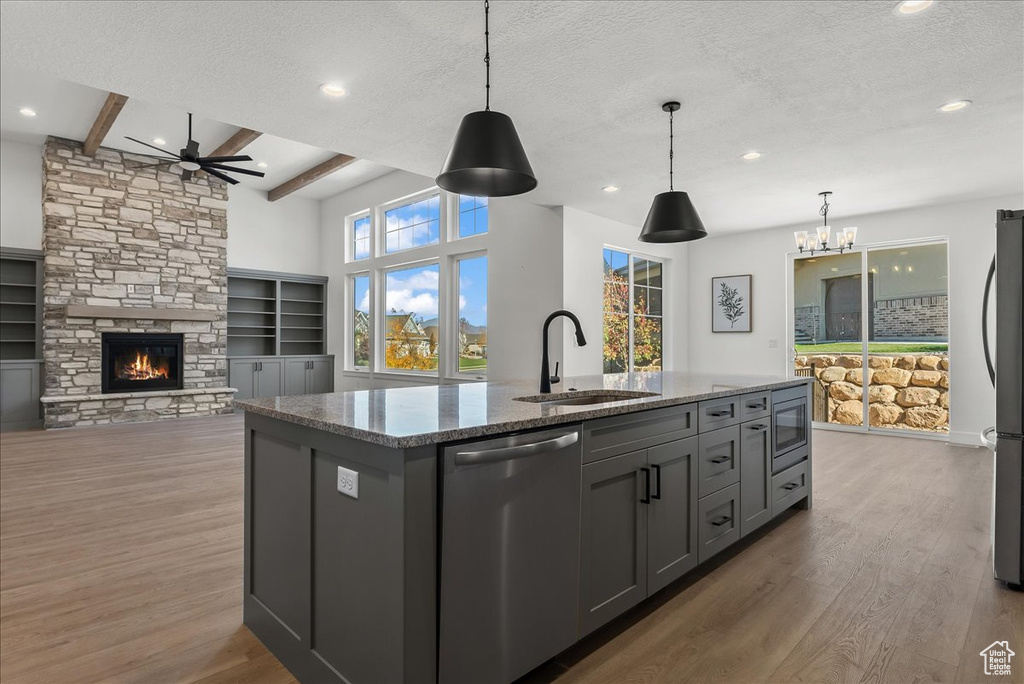 Kitchen featuring stone countertops, hardwood / wood-style flooring, stainless steel appliances, and a stone fireplace