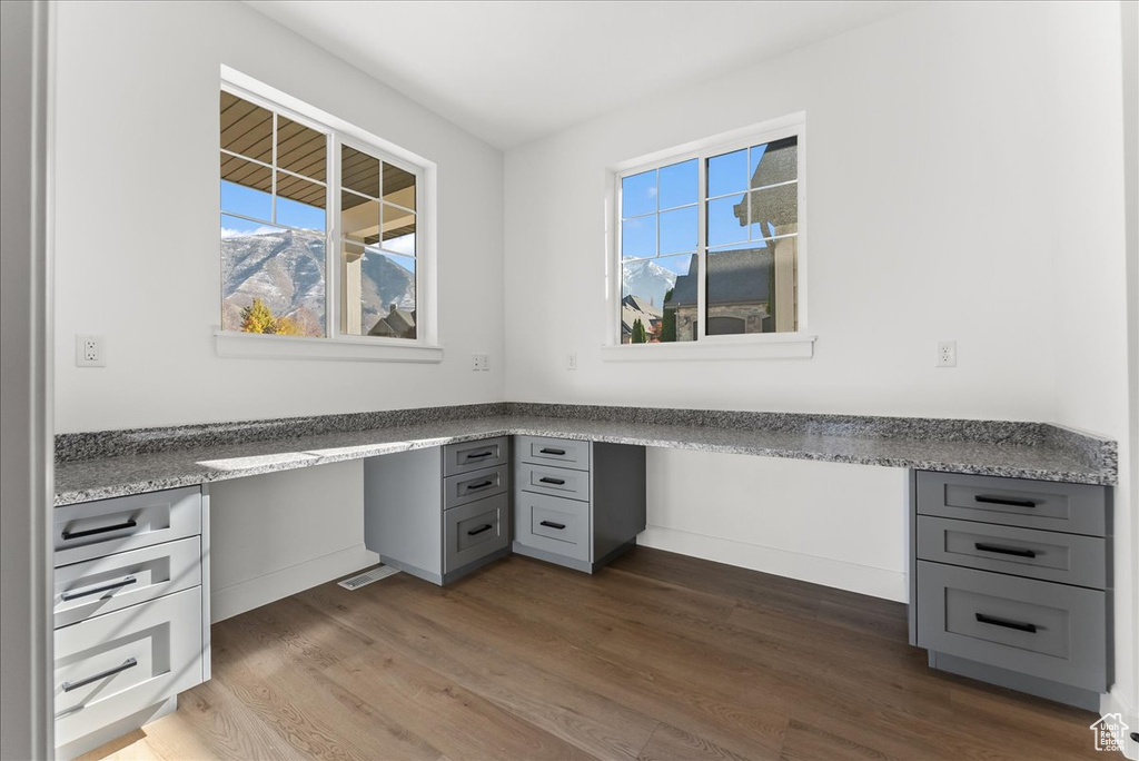 Unfurnished office featuring hardwood / wood-style floors and built in desk