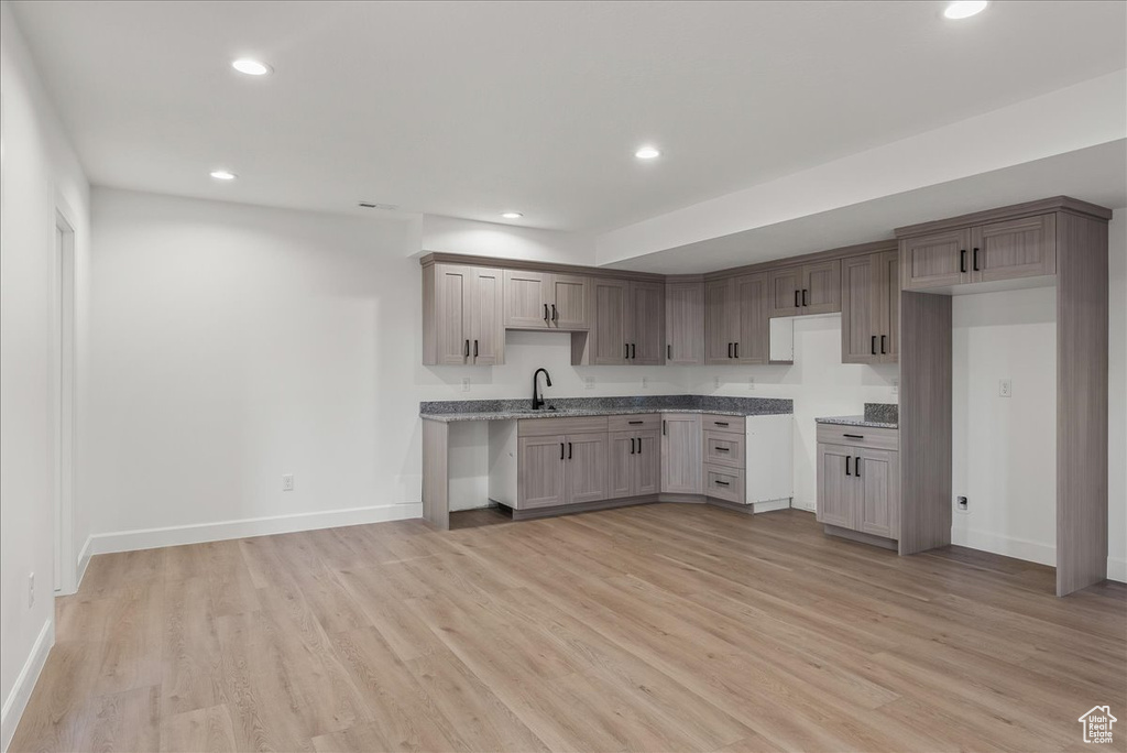 Kitchen with light hardwood / wood-style floors, sink, and light stone counters