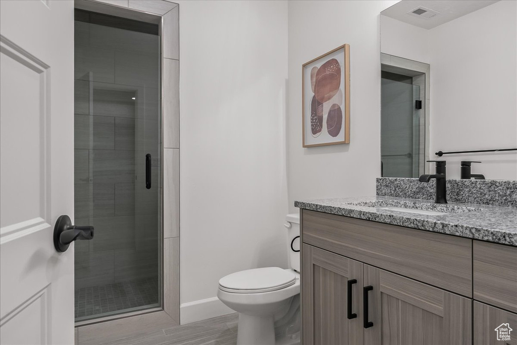 Bathroom featuring vanity, walk in shower, and toilet